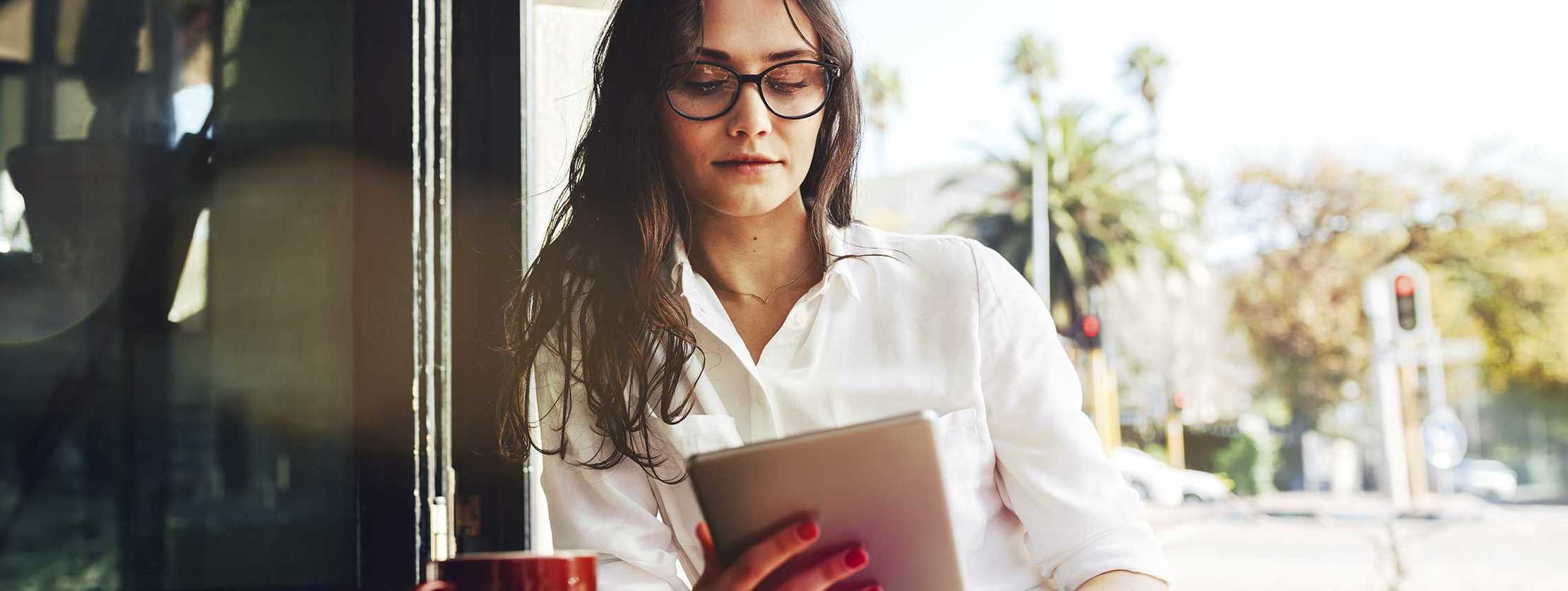 Junge Frau liest etwas auf ihrem Tablet in einem Café Junge Frau liest etwas auf ihrem Tablet in einem Café