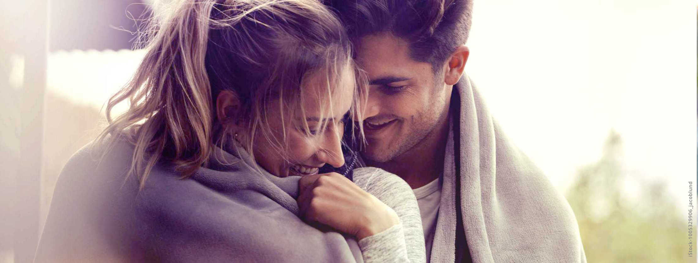 MS und ich: Ein Mann nimmt seine Partnerin liebevoll in den Arm. Bei sind in eine Decke gehüllt MS und ich: Ein Mann nimmt seine Partnerin liebevoll in den Arm. Bei sind in eine Decke gehüllt