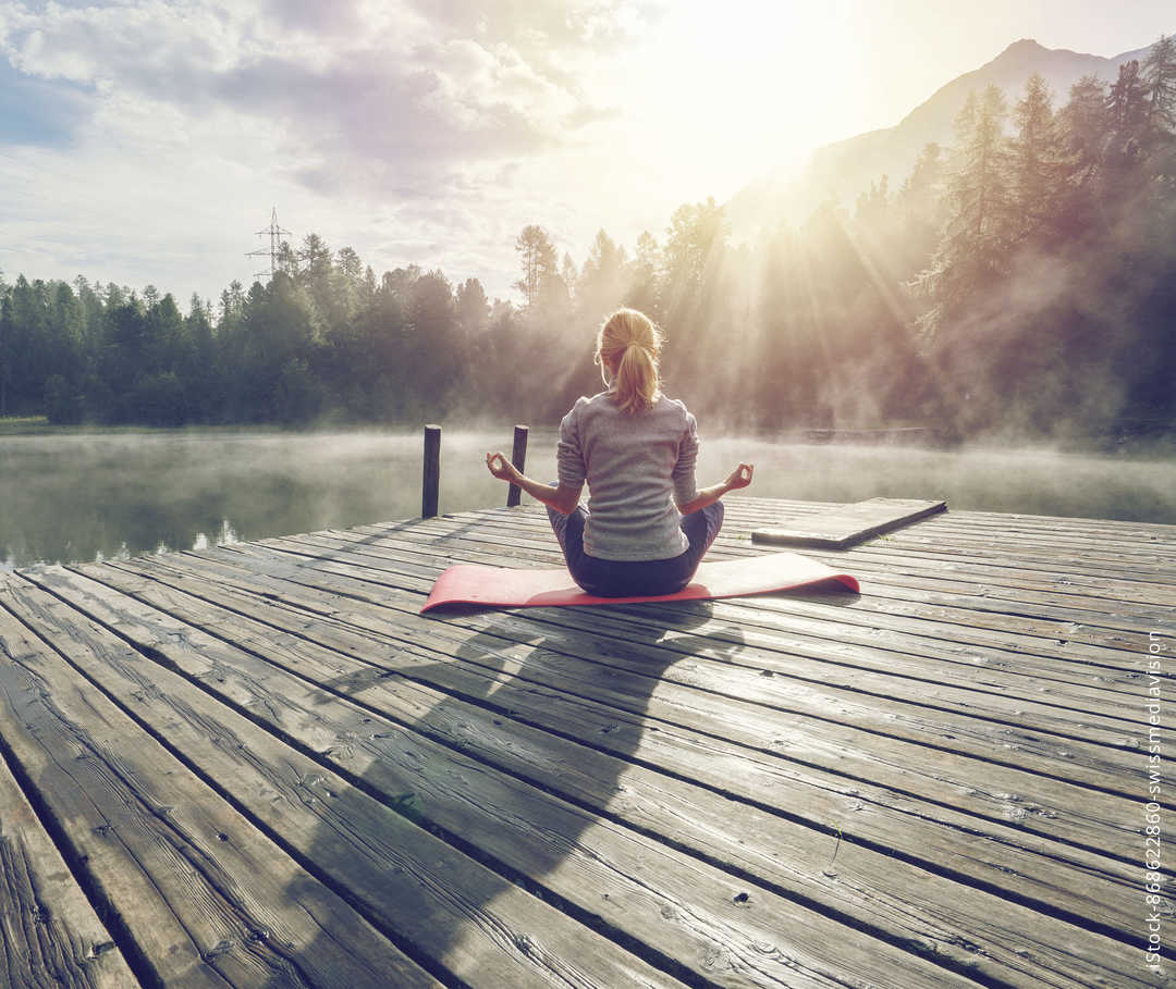 Eine blonde Frau macht Yoga auf einem Steg am See Eine blonde Frau macht Yoga auf einem Steg am See